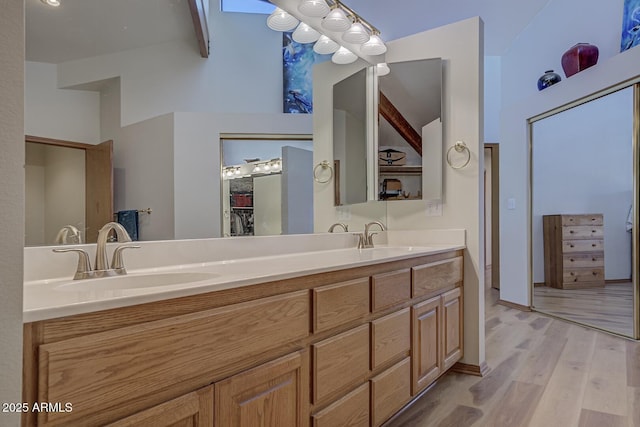 bathroom with double vanity, wood finished floors, beamed ceiling, and a sink