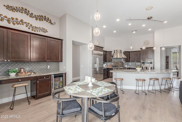 8725 E Menlo Cir, Mesa, AZ 85207 - kitchen with wine cooler, wall chimney exhaust hood, stainless steel appliances, dark brown cabinets, and light wood finished floors