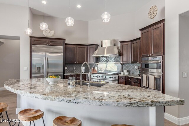 8725 E Menlo Cir, Mesa, AZ 85207 - kitchen featuring stainless steel appliances, wall chimney exhaust hood, baseboards, a breakfast bar area, and recessed lighting