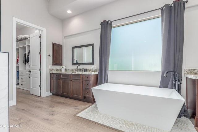 8725 E Menlo Cir, Mesa, AZ 85207 - bathroom featuring wood finished floors, vanity, a soaking tub, recessed lighting, and a spacious closet
