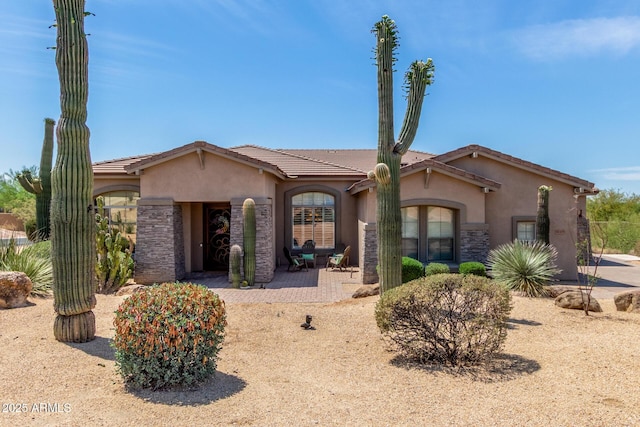 8725 E Menlo Cir, Mesa, AZ 85207 - view of front of house featuring stucco siding, stone siding, a patio area, and a tile roof