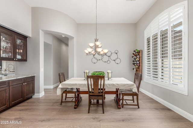 8725 E Menlo Cir, Mesa, AZ 85207 - dining room featuring light wood finished floors, a chandelier, arched walkways, and baseboards