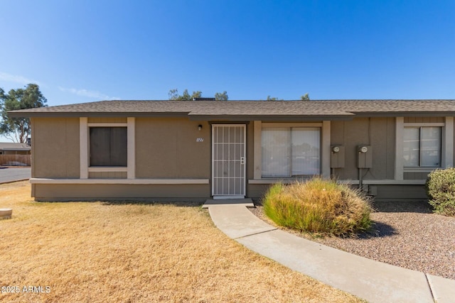 ranch-style home with roof with shingles and a front lawn