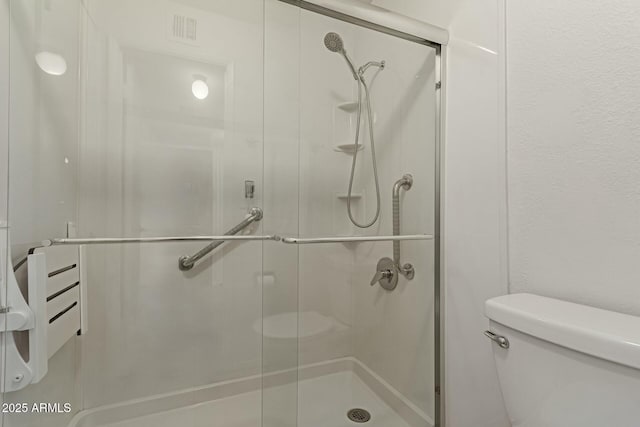 bathroom with visible vents, a shower stall, and toilet