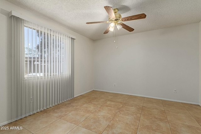 empty room with light tile patterned floors, a textured ceiling, and baseboards