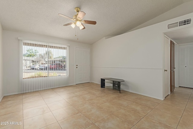 unfurnished room with lofted ceiling, ceiling fan, a textured ceiling, light tile patterned flooring, and visible vents