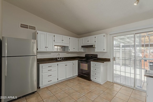 kitchen featuring freestanding refrigerator, black range with electric stovetop, dark countertops, and a sink