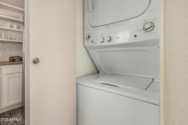 laundry area featuring dark hardwood / wood-style flooring and stacked washer / drying machine