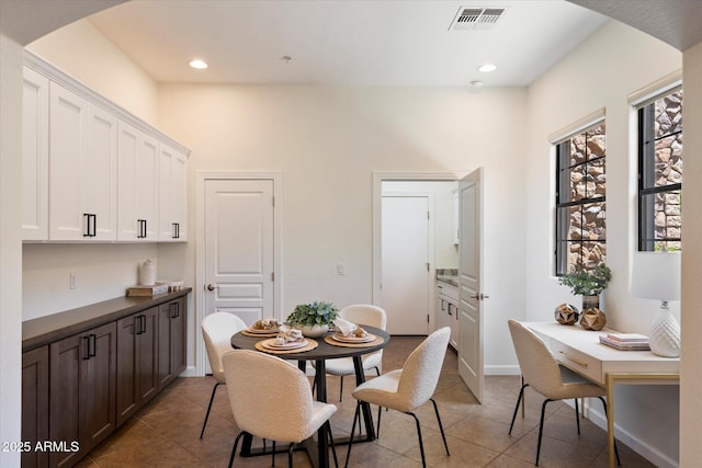tiled dining area featuring arched walkways, visible vents, and recessed lighting