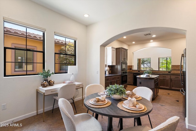 dining space featuring arched walkways, recessed lighting, baseboards, light tile patterned floors, and visible vents