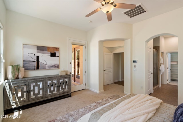 carpeted bedroom featuring arched walkways, baseboards, and visible vents