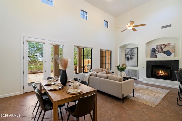 tiled dining area with visible vents, a wealth of natural light, and a towering ceiling