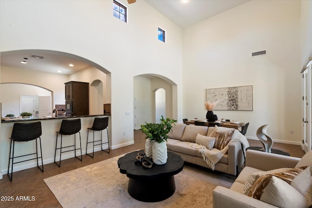 living area with a towering ceiling, baseboards, and visible vents