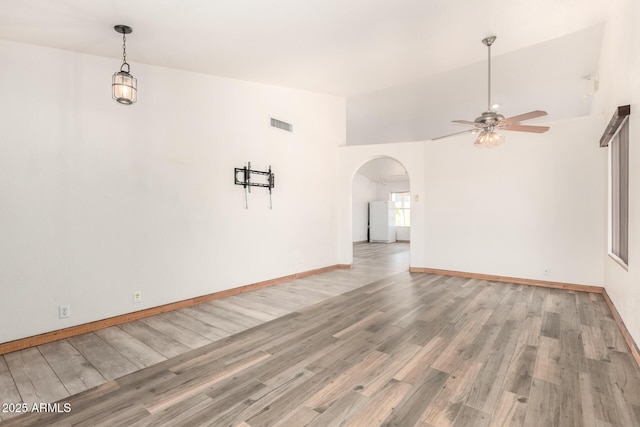 2356 N Glenview, Mesa, AZ 85213 - unfurnished living room featuring visible vents, baseboards, arched walkways, light wood-type flooring, and a ceiling fan