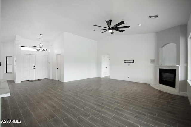 unfurnished living room featuring ceiling fan, dark hardwood / wood-style flooring, and a towering ceiling