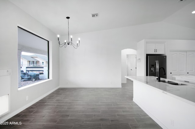 unfurnished dining area with lofted ceiling, a chandelier, and sink