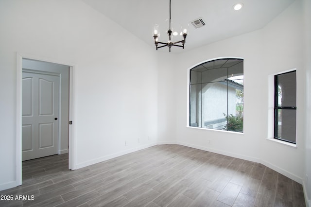 spare room featuring hardwood / wood-style floors and a notable chandelier