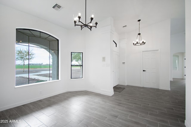 interior space with a notable chandelier, dark wood-type flooring, and a high ceiling