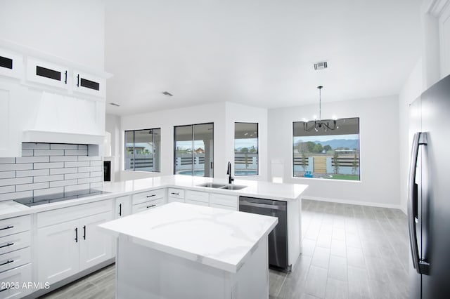 kitchen featuring appliances with stainless steel finishes, sink, white cabinets, hanging light fixtures, and a center island