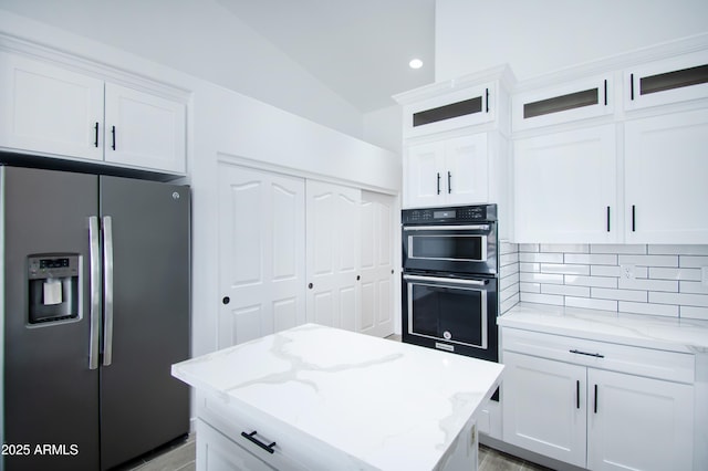 kitchen with white cabinetry, stainless steel fridge, light stone counters, and double oven