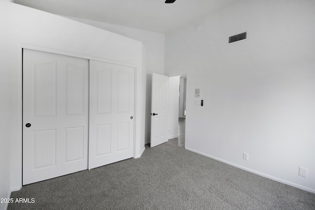 unfurnished bedroom featuring dark carpet and a closet