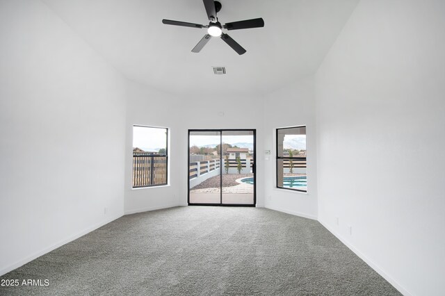 spare room with carpet flooring, ceiling fan, and a towering ceiling