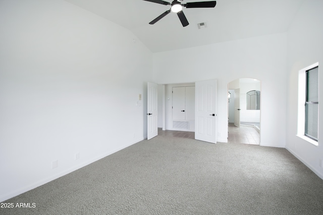 unfurnished bedroom featuring light carpet, connected bathroom, high vaulted ceiling, and ceiling fan