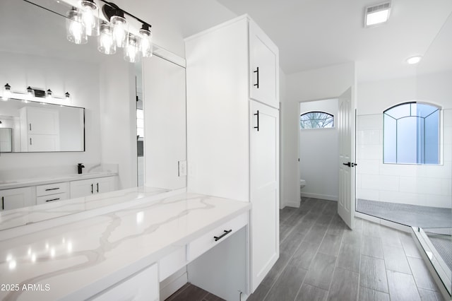 bathroom featuring tiled shower, vanity, and toilet