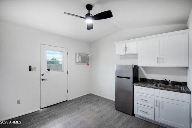 kitchen with sink, white cabinetry, vaulted ceiling, an AC wall unit, and stainless steel fridge