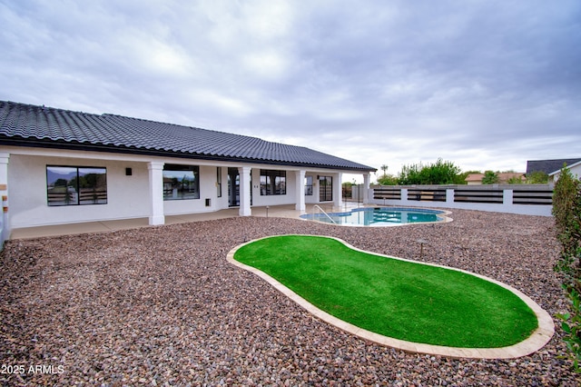 rear view of property with a fenced in pool and a patio area