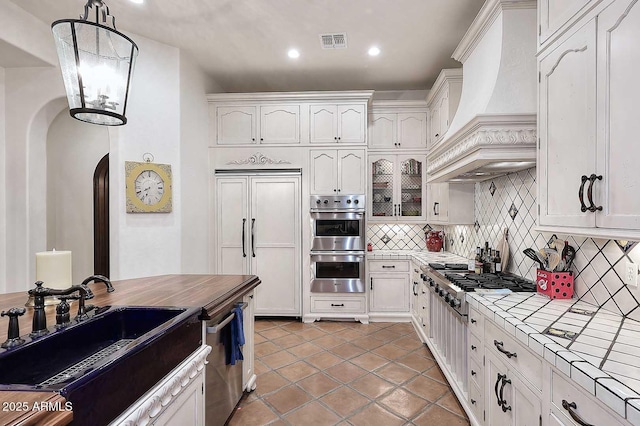 2041 W Hemlock Way, Chandler, AZ 85248 - kitchen with tile counters, custom range hood, appliances with stainless steel finishes, a sink, and arched walkways