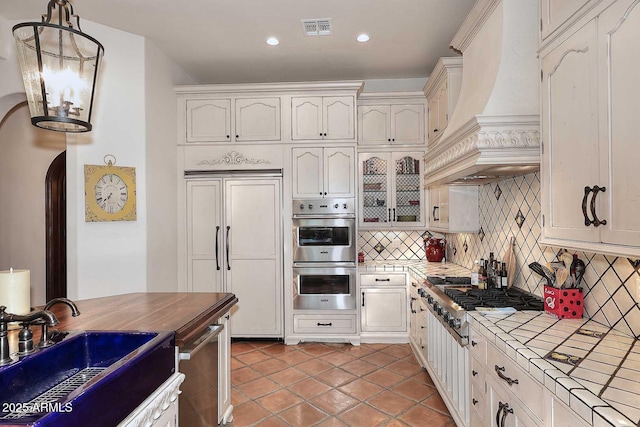 2041 W Hemlock Way, Chandler, AZ 85248 - kitchen featuring tile countertops, custom range hood, appliances with stainless steel finishes, a sink, and backsplash