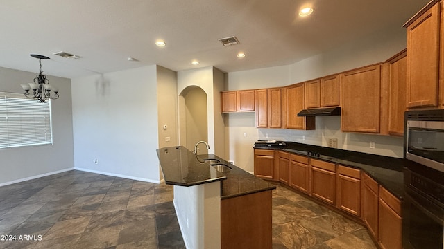 kitchen with sink, a notable chandelier, dark stone countertops, decorative light fixtures, and black appliances