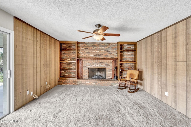 unfurnished living room featuring carpet flooring, a fireplace, and wood walls