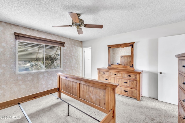 bedroom with ceiling fan, light colored carpet, baseboards, and a textured ceiling