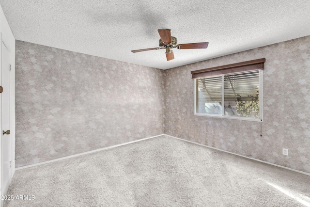 carpeted spare room with wallpapered walls, a ceiling fan, baseboards, and a textured ceiling