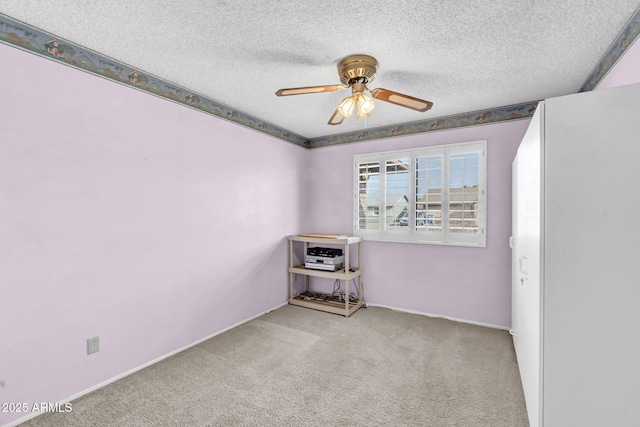 empty room with ceiling fan, carpet, and a textured ceiling