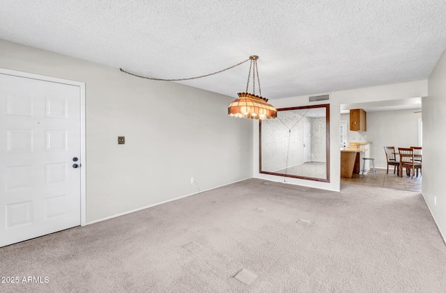 unfurnished dining area featuring visible vents, light colored carpet, and a textured ceiling