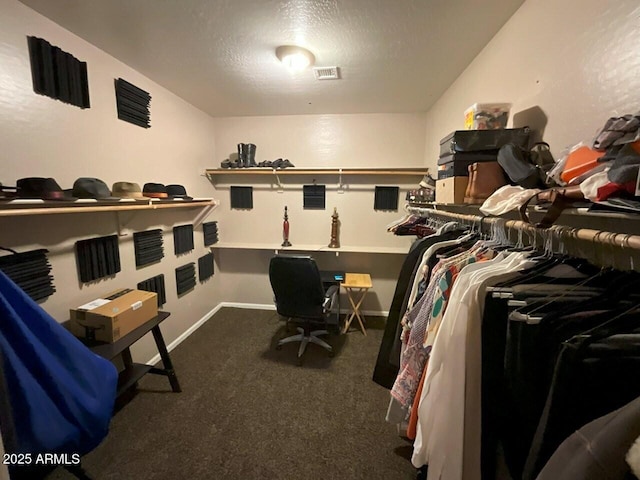 walk in closet featuring dark carpet