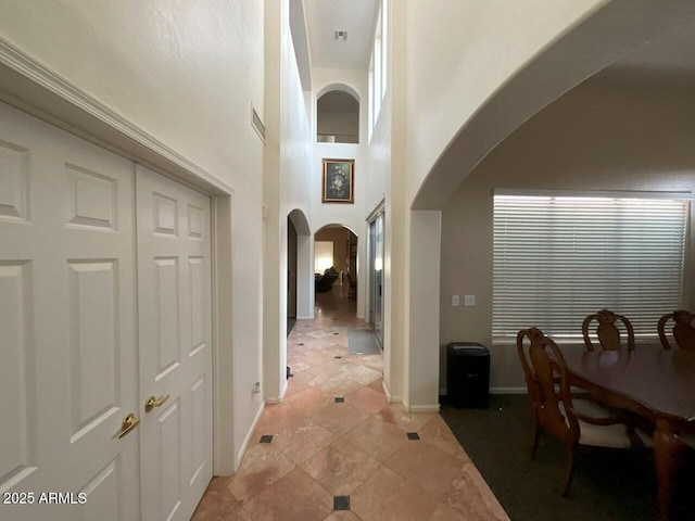 hallway with light tile patterned floors and a high ceiling