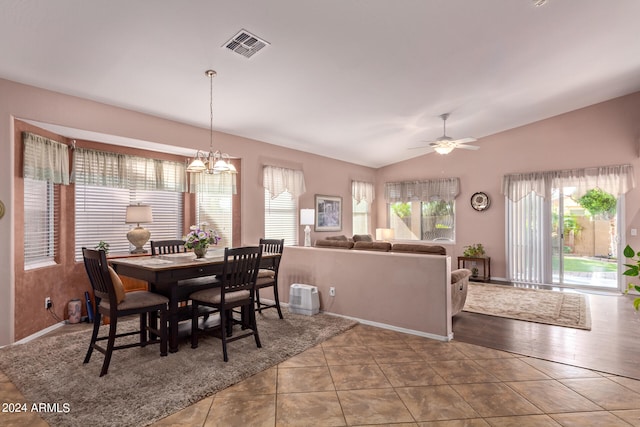 tiled dining area with ceiling fan with notable chandelier and vaulted ceiling