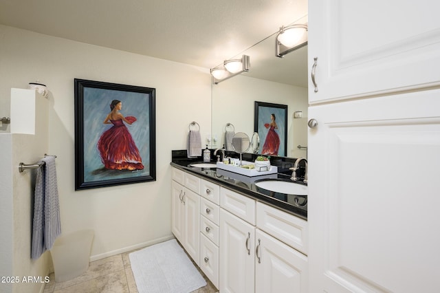 full bath with double vanity, tile patterned floors, baseboards, and a sink