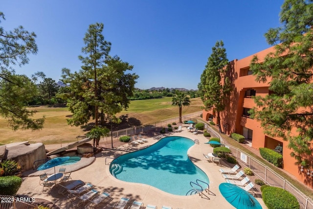 community pool with a fenced backyard and a patio area