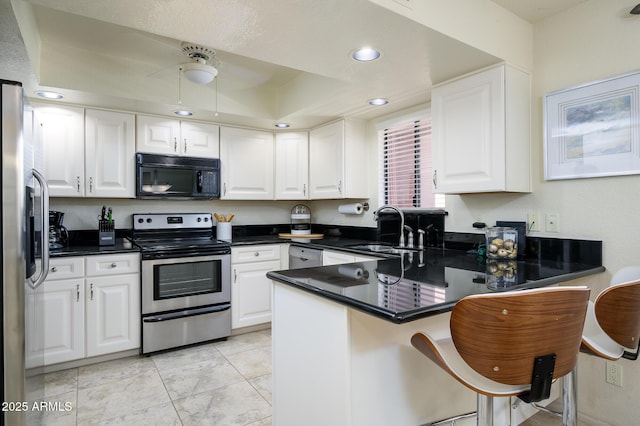 kitchen featuring a sink, appliances with stainless steel finishes, a peninsula, and white cabinetry