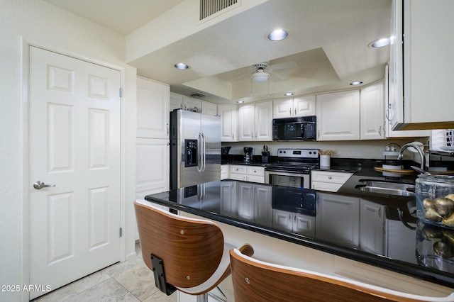 kitchen with visible vents, a sink, a tray ceiling, stainless steel appliances, and white cabinets