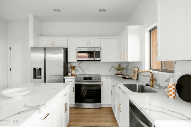 kitchen with sink, light stone counters, white cabinets, and appliances with stainless steel finishes