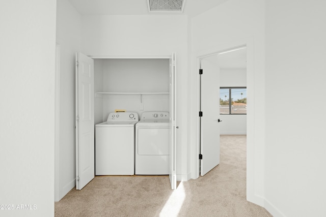 clothes washing area featuring light colored carpet and separate washer and dryer