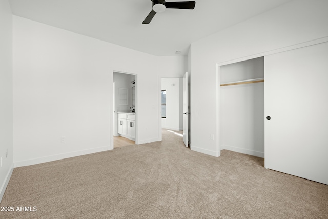 unfurnished bedroom with a closet, ceiling fan, light colored carpet, and ensuite bath