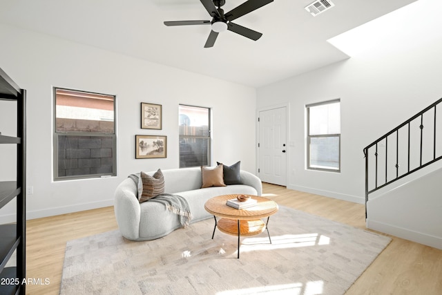 living room with light wood-type flooring, ceiling fan, and plenty of natural light