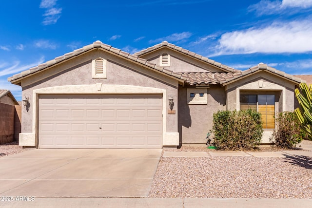 view of front facade featuring concrete driveway, a tile roof, an attached garage, and stucco siding